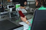 Frau an der Kasse kontrolliert mit der Alterskontrollscheibe das Mindestalters eines Kunden